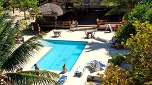 Un área de piscina con sillones de descanso y una zona de estar cubierta.