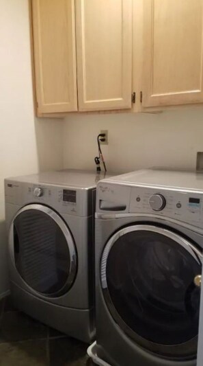 A laundry area with two front-loading washing machines and wooden cabinets above. - Silver Lake Hidden Jewel (Los Angeles)