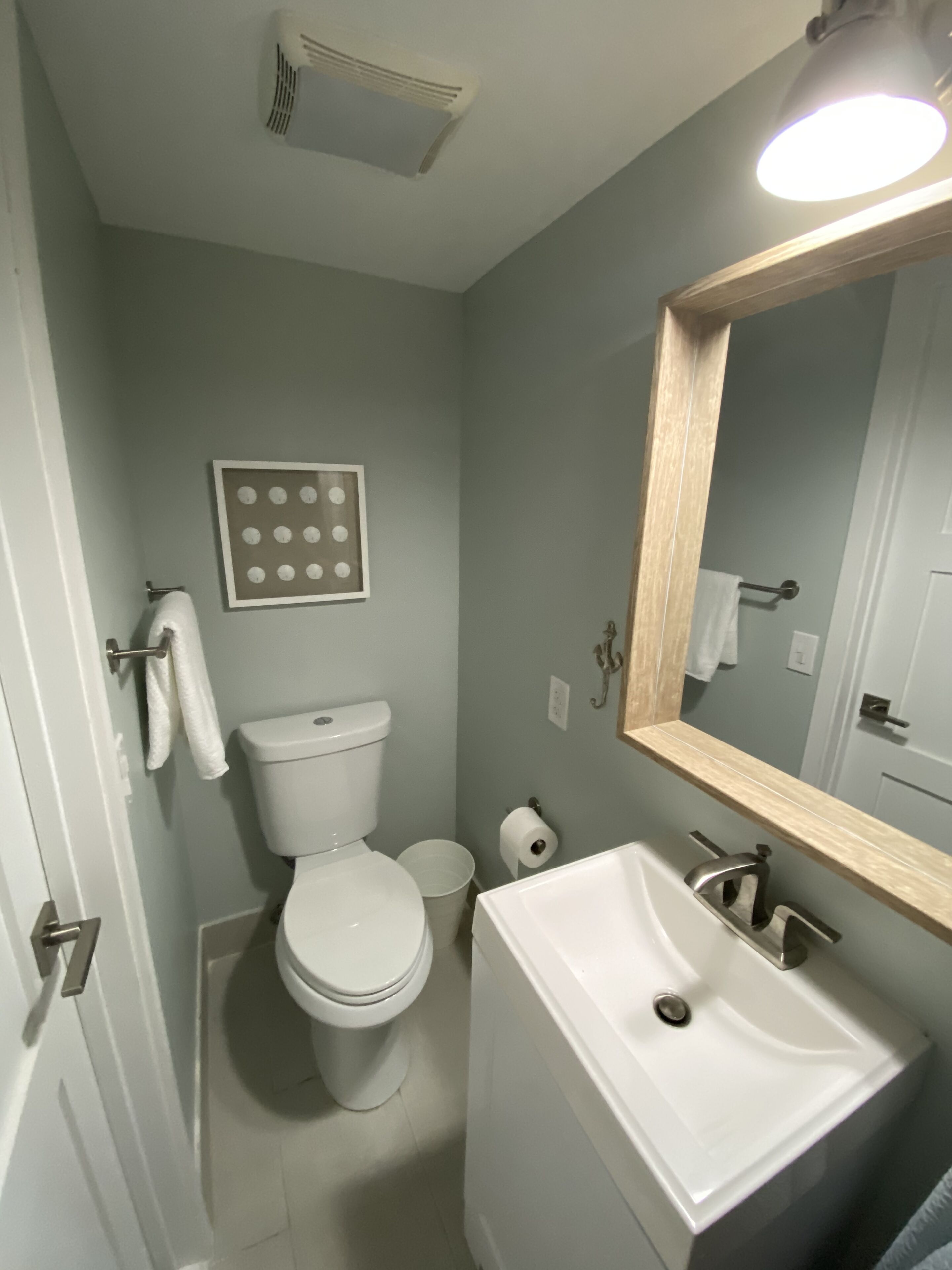 A small bathroom with a toilet, sink, and mirror.
