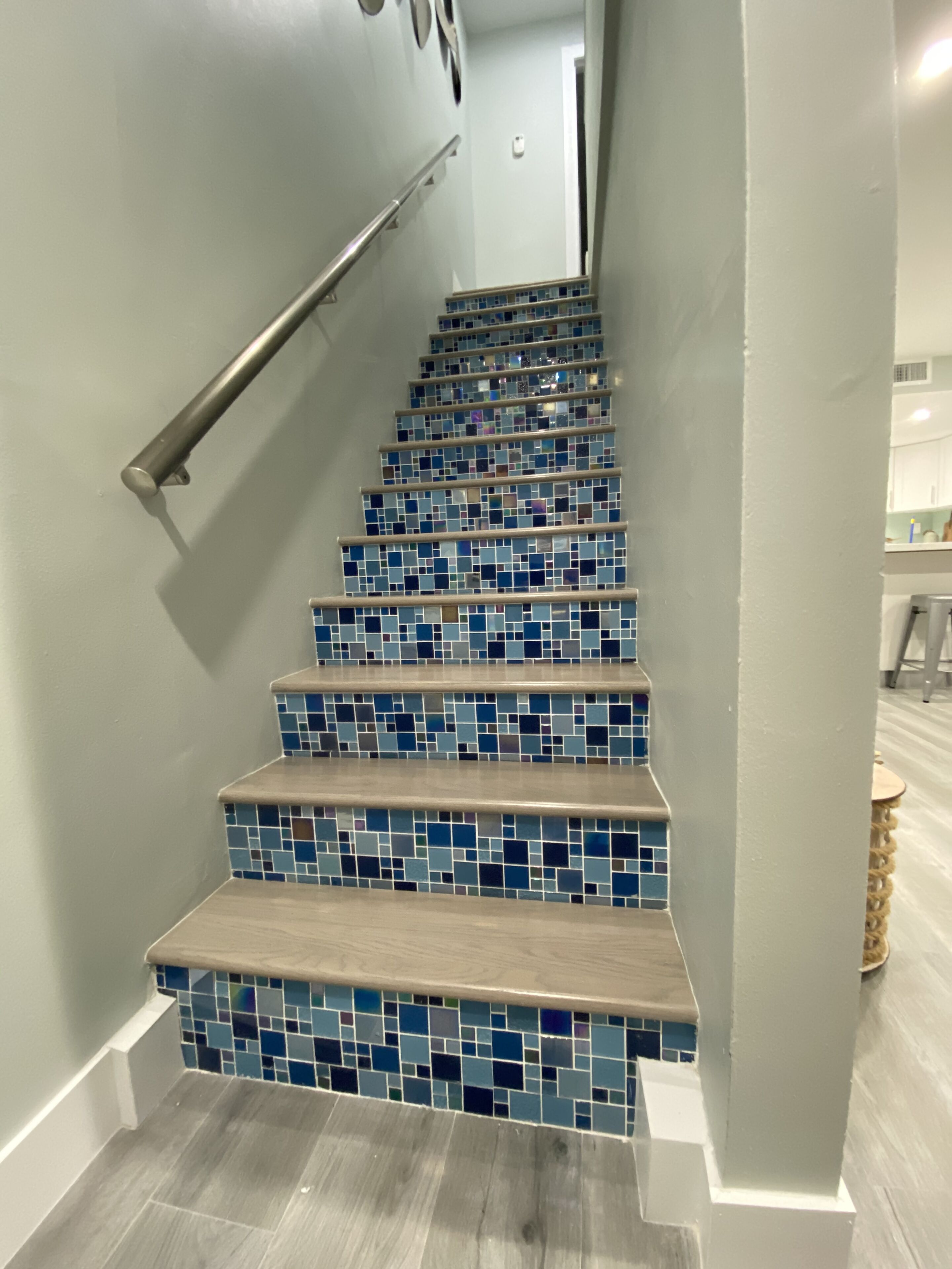 A staircase with blue-tiled steps and a wooden handrail.