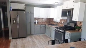 A modern kitchen with grey cabinets, a stainless steel refrigerator, a gas stove, and a microwave.