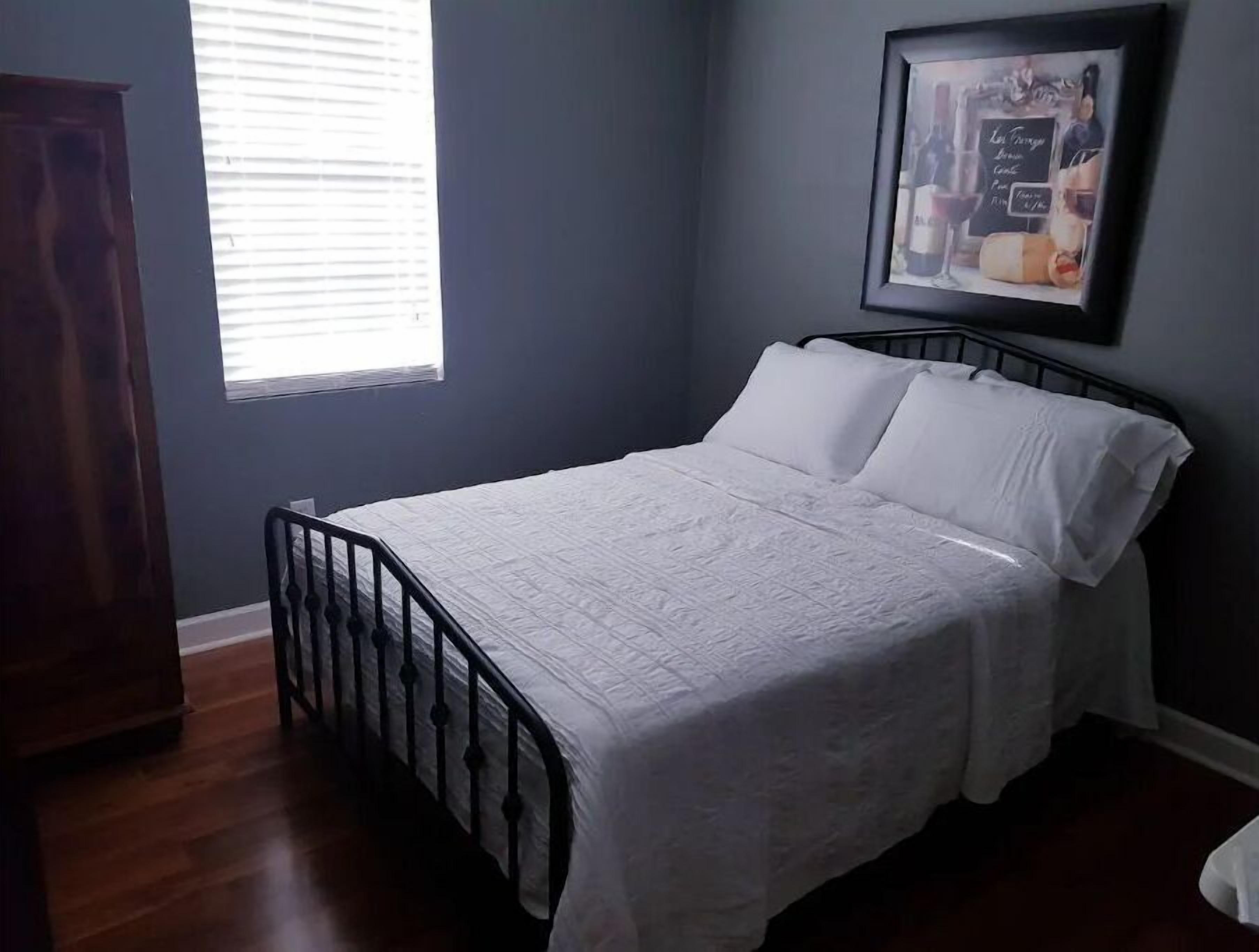 A bedroom with a bed, a window, and a framed picture on the wall.