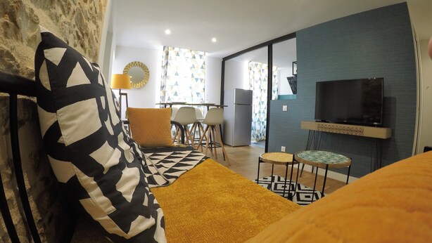 Ein modernes Wohnzimmer mit Sofa, Fernseher und einem Essbereich mit Stühlen und Tisch.