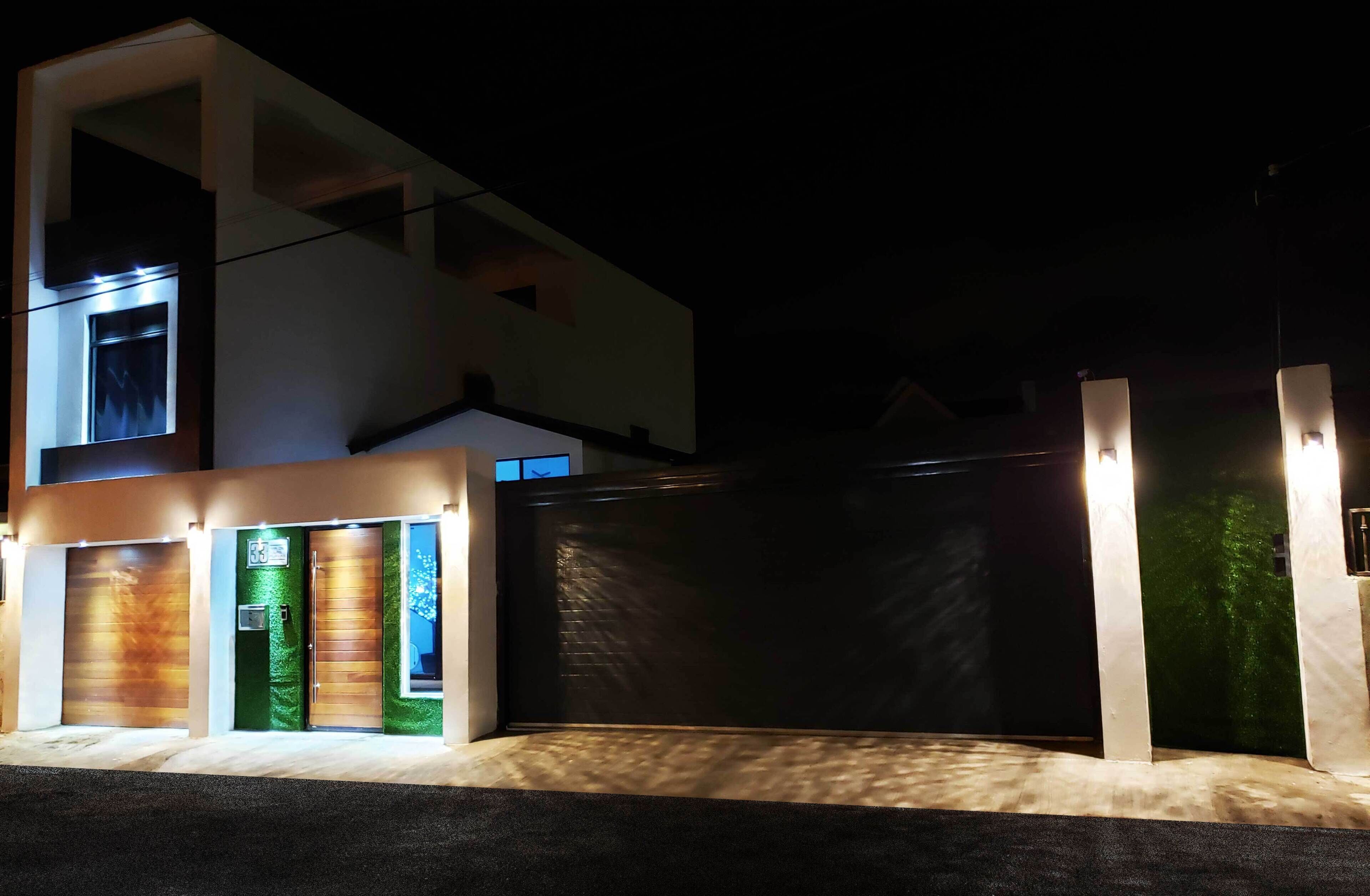 A modern building with a gated entrance, a visible garage door, and a well-lit facade.