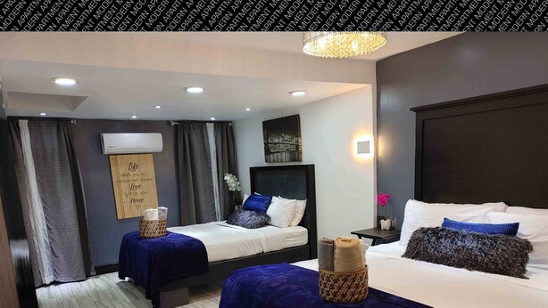 A hotel room with two beds, a large window, a chandelier, and a wall-mounted air conditioner. - Villas Beach House(next to the main Blvd. walking distance to the beach & A/C) (Rosarito)