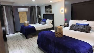 Une chambre d’hôtel avec deux lits, une grande fenêtre avec des rideaux, un climatiseur fixé au mur et un panneau décoratif.