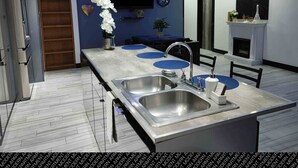 A modern kitchen with a central island, stainless steel sinks, and pendant lighting. - Villas Beach House(next to the main Blvd. walking distance to the beach & A/C) (Rosarito)