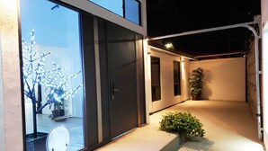 A modern building with a glass door, a small potted plant, and a pathway leading to a door. - Villas Beach House(next to the main Blvd. walking distance to the beach & A/C) (Rosarito)