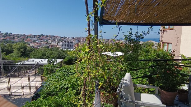 Un balcón con vistas a un paisaje urbano, que incluye edificios y una costa lejana.