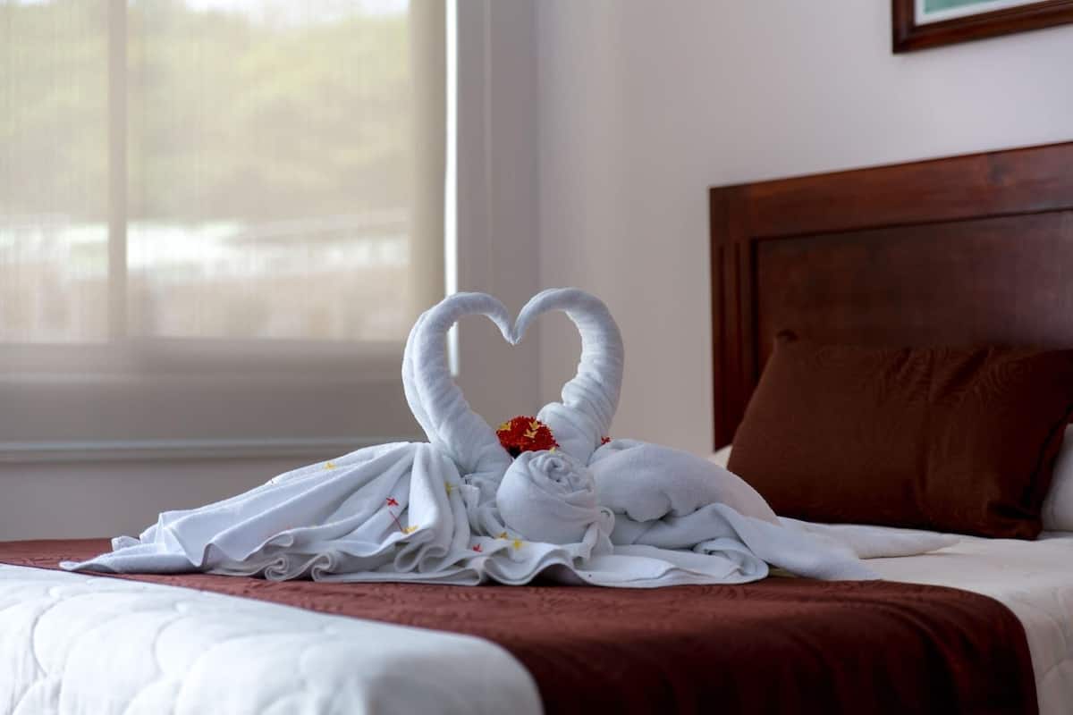 A neatly made bed with a brown headboard and a white quilt.