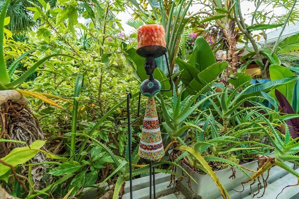 Un adorno colgante con borlas de cuentas en un exuberante jardín interior.