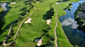 A golf course with sand bunkers, water hazards, and palm trees. - The Lewis Properties (West Palm Beach)