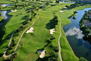 Un campo da golf con bunker di sabbia, ostacoli d'acqua e palme.