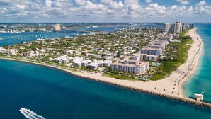 An aerial view of a coastal resort with beachfront villas, a pier, and a beach. - NEW Luxurious Condo/inlet & Ocean Views 106 Inlet Way Unit 103 - Palm Beach Shores (Singer Island)