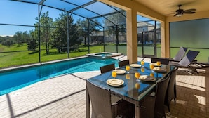 A covered outdoor area with a pool, dining table set for four, and two ceiling fans. - Welcome to The Windsor Dream! (Kissimmee)