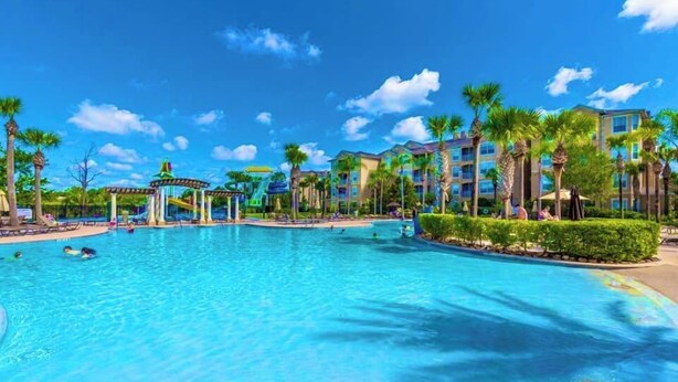 A large swimming pool surrounded by palm trees and a gazebo. - Welcome to The Windsor Dream! (Kissimmee)