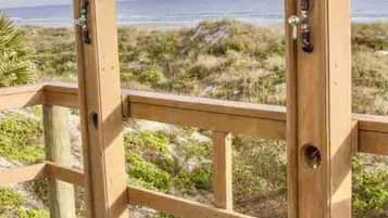 A wooden deck with a view of the beach and ocean.