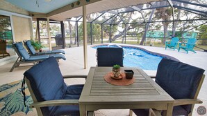 Eine überdachte Terrasse mit Pool, Liegestühlen und einem Tisch mit einer Pflanze.