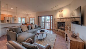 A spacious living room with a sectional sofa, a round coffee table, and a stone fireplace.