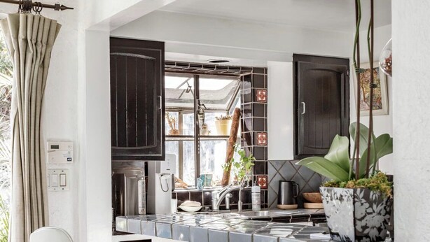 Una cocina moderna con una isla central, sillas blancas y un armario de madera.