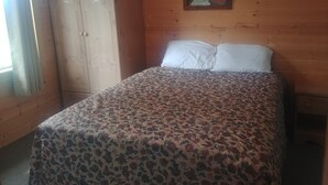 A room with a bed, a wardrobe, and a painting on the wall.