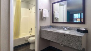 A bathroom with a bathtub, toilet, sink, and a large mirror. - Rodeway Inn (Augusta)