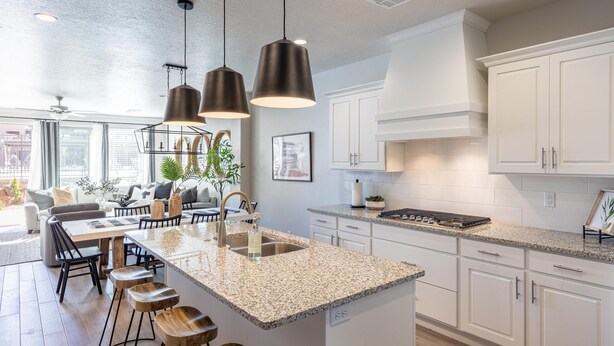 A modern kitchen with white cabinets, granite countertops, and a central island with stools. - Poolside Escape At The Ledges (St. George)