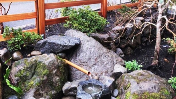 A rock garden with a small pond, moss-covered rocks, and a wooden rake. - Zen themed private retreat in NW Portland. (Portland)