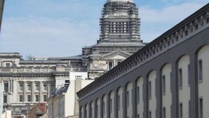 A street view with a building featuring a large dome and a row of flags. - Double room with balcony in the heart of Brussels (Bruxelles)
