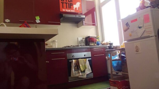 A kitchen with red cabinets, a stove, a refrigerator, and a window. - Double room with balcony in the heart of Brussels (Bruxelles)