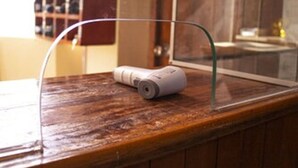 A wooden counter with a white device, possibly a phone or remote control, and a glass display case. - Hospedaje Ollantays (Cusco)