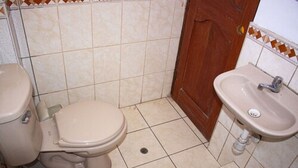 A small bathroom with a toilet, sink, and tiled walls. - Hospedaje Ollantays (Cusco)