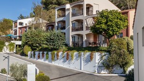 A multi-story residential building with balconies, surrounded by greenery and trees.