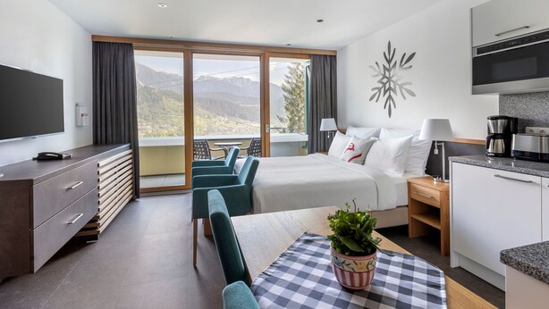 Ein modernes Hotelzimmer mit Bett, Schreibtisch, Essbereich und einer Küche.