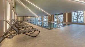 Ein geräumiger Innenbereich mit einer langen Reihe aus Metallliegestühlen entlang einer Wand, einem Glasgeländer mit Blick auf eine untere Ebene und einem modernen Deckengestalt.