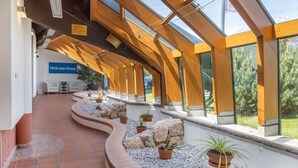 A modern building with a curved pathway lined with potted plants and rocks, leading to a reception area with a 'Welcome Home' sign. - 1-Bed Apartment | Schladming Ski Resort | Sleeps 4 (Schladming)