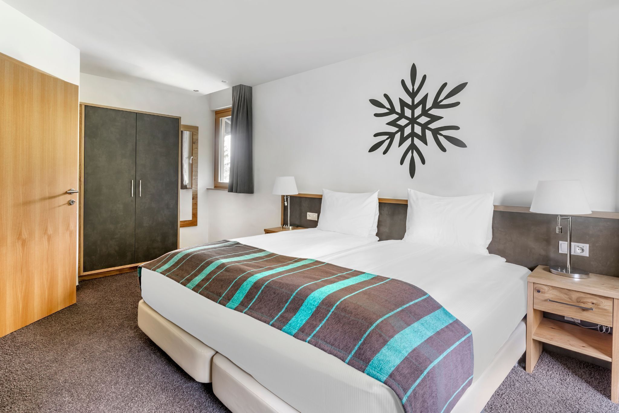 Una camera d'albergo con un letto grande, un armadio, un comodino e un elemento decorativo a parete.