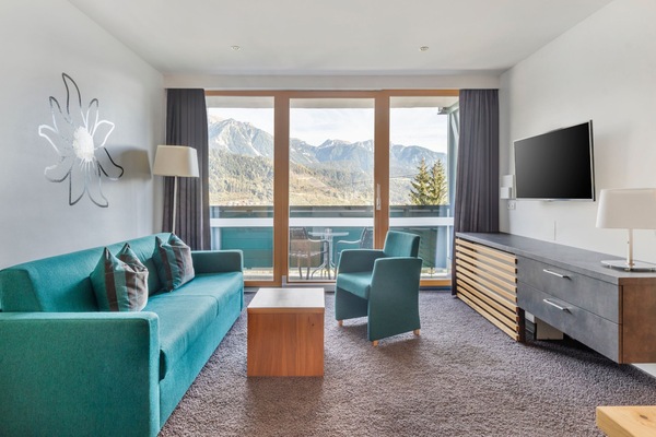 This cozy 1-bedroom apartment in Schladming features a spacious living area with two single beds, a smart TV, and a fully equipped kitchen, complemented by a balcony offering breathtaking views of the surrounding mountains and forests.