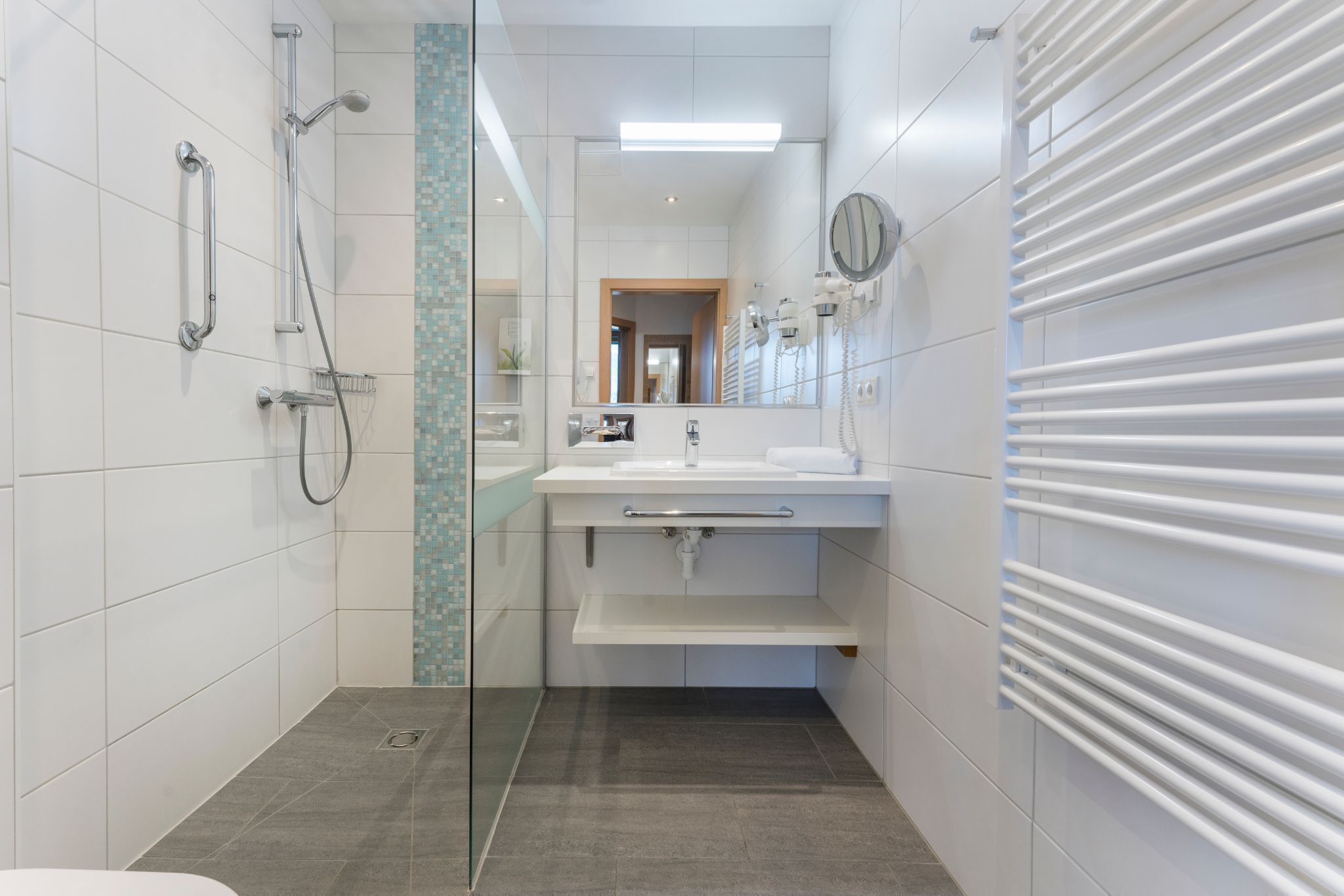 A modern bathroom with a shower, a sink with a mirror, and a towel rack.