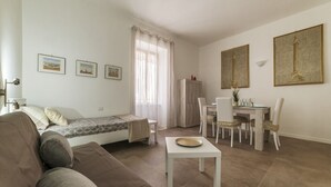 A compact living space with a sofa, a small dining table, a bed, and a kitchenette. - GuestHost - Elegant and modern 60sqm apartment that can accommodate up to 4 people. Located on the third floor, with elevator (not suitable for disabled people), of a characteristic building in San Lorenzo area, the apartment is about 15 minutes walk fro (Roma)