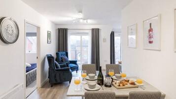 A dining area with a table set for breakfast, including croissants and orange juice.