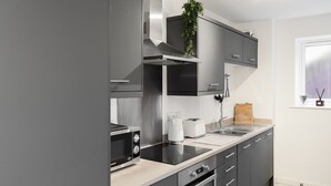 Une cuisine moderne avec des meubles gris, des appareils en acier inoxydable et une fenêtre offrant une belle vue.