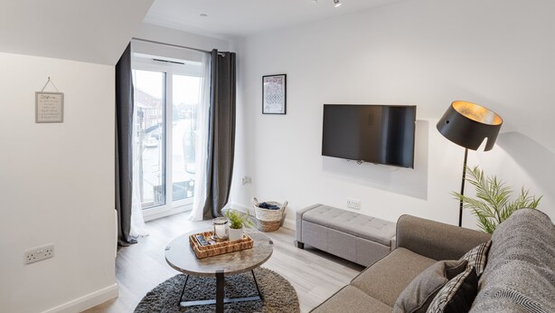 Un salon moderne avec un téléviseur à écran plat, un canapé, une table basse et un lampadaire.