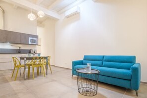 Une cuisine moderne avec un coin repas, un canapé bleu et une petite table ronde sur laquelle se trouve une carafe en verre.