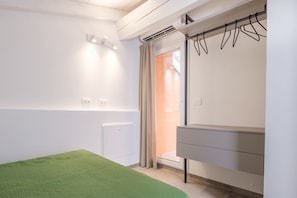 Une chambre à coucher avec un lit, une commode, un radiateur et une fenêtre avec des rideaux.