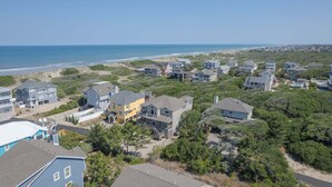 A coastal residential area with houses, a beach, and a clear sky. - 1818 - It's A Shore Thing, 70 Yards to Beach | Pool, Hot Tub & Elevator (Corolla)