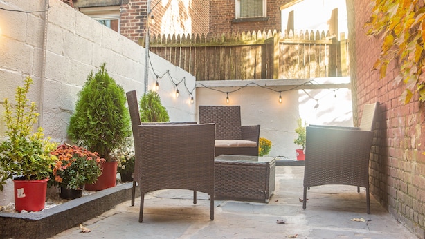 A patio with wicker furniture, potted plants, and string lights.