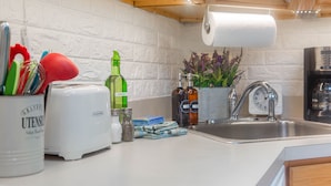 A kitchen with a white countertop, a toaster, a sink, and various kitchen items like bottles and utensils.