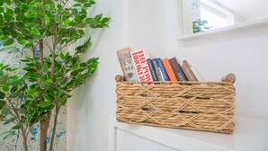 A wicker basket filled with books on a white shelf.