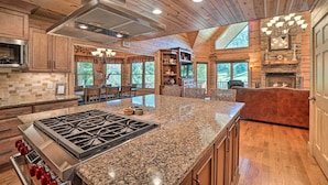 Una cocina amplia con encimeras de granito, estufa de acero inoxidable, armarios de madera y una isla grande.
